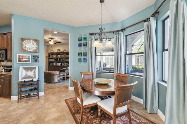 dining room featuring ceiling fan with notable chandelier, light tile patterned floors, and a textured ceiling