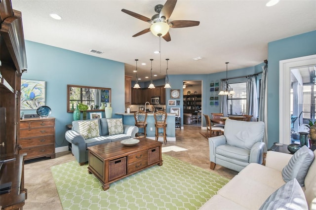 living room with a textured ceiling, ceiling fan with notable chandelier, and sink