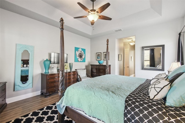 bedroom featuring a tray ceiling, ceiling fan, and dark wood-type flooring