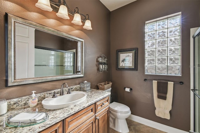 bathroom with tile patterned floors, vanity, an enclosed shower, and toilet