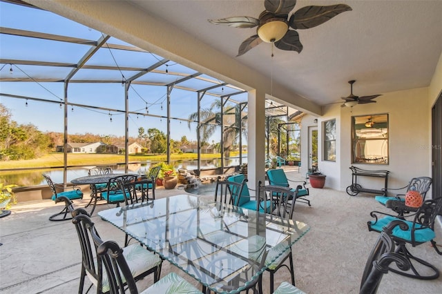 view of patio / terrace featuring a lanai, ceiling fan, and a water view