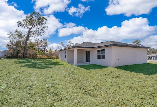 back of house featuring a patio, a lawn, fence, and stucco siding