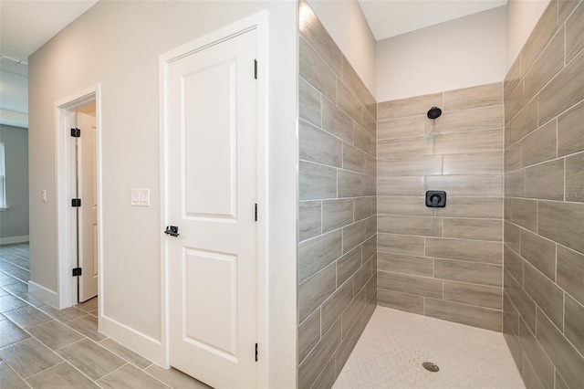 bathroom with tiled shower and baseboards