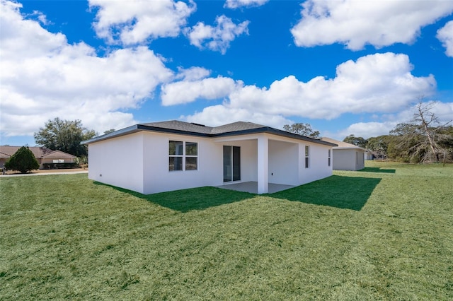 rear view of house featuring a lawn, a patio area, and stucco siding