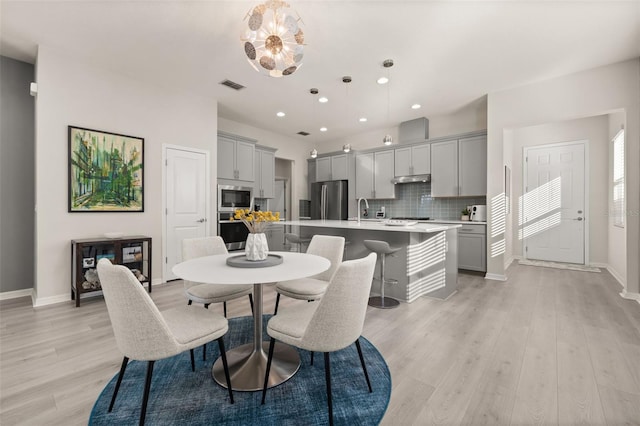 dining room with light hardwood / wood-style flooring, a notable chandelier, and sink