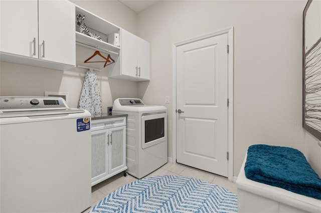 clothes washing area featuring cabinets, light tile patterned floors, and separate washer and dryer