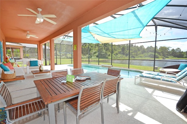 view of patio / terrace featuring a lanai, ceiling fan, a water view, and an outdoor living space