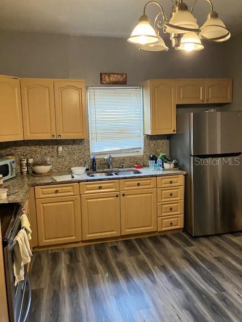 kitchen featuring stainless steel appliances, sink, a chandelier, dark hardwood / wood-style floors, and hanging light fixtures