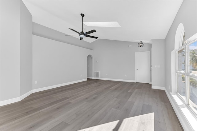 unfurnished living room featuring hardwood / wood-style floors, ceiling fan with notable chandelier, and vaulted ceiling