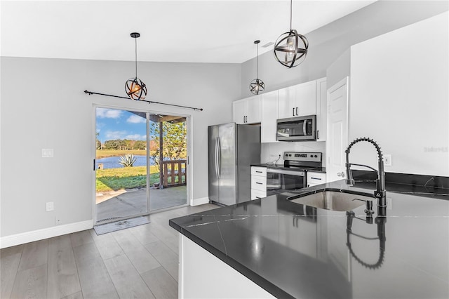 kitchen featuring white cabinets, sink, hanging light fixtures, vaulted ceiling, and stainless steel appliances