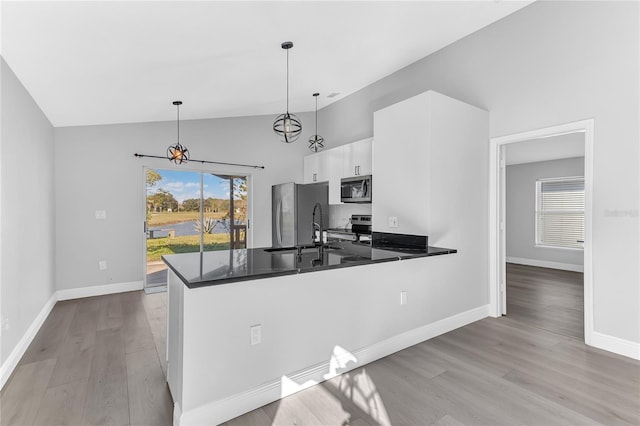 kitchen featuring white cabinets, hanging light fixtures, appliances with stainless steel finishes, light hardwood / wood-style floors, and kitchen peninsula