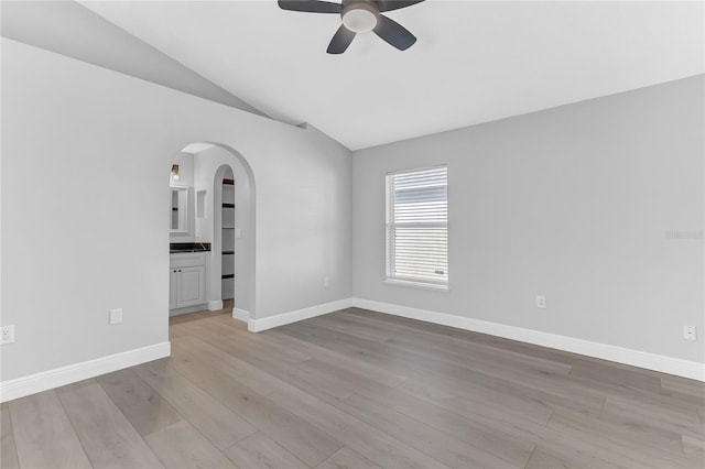 empty room with ceiling fan, light wood-type flooring, and lofted ceiling