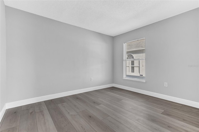 empty room featuring a textured ceiling and light hardwood / wood-style flooring