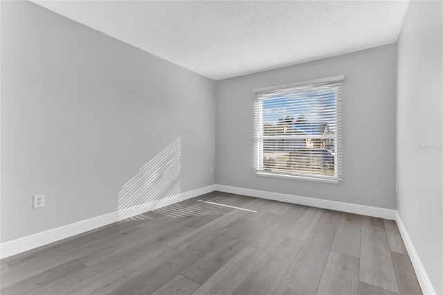 empty room with a textured ceiling and light wood-type flooring