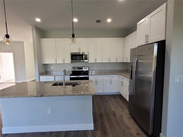 kitchen featuring light stone countertops, appliances with stainless steel finishes, sink, pendant lighting, and white cabinets