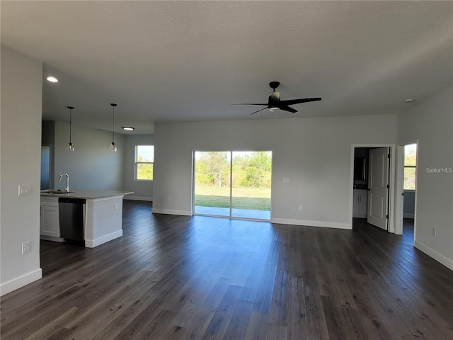 unfurnished living room with ceiling fan, dark hardwood / wood-style flooring, and sink