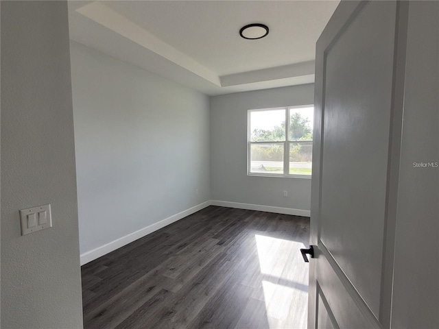 unfurnished room with dark hardwood / wood-style flooring and a raised ceiling