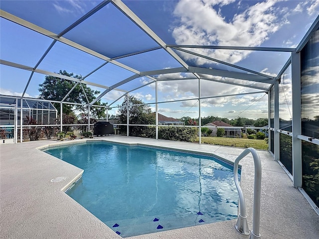 view of pool with glass enclosure and a patio area