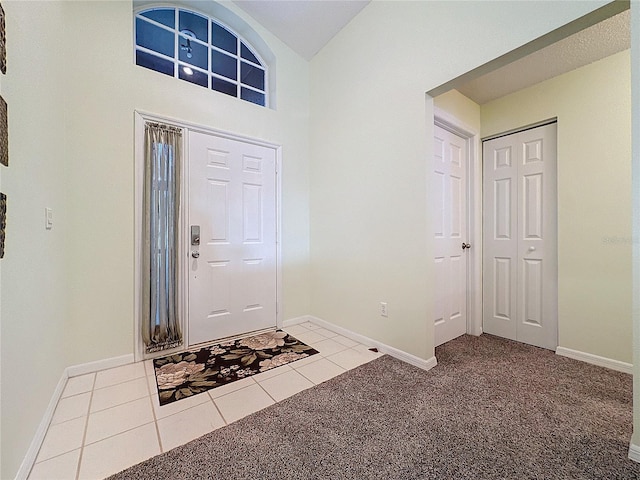 foyer entrance with light tile patterned floors and a towering ceiling