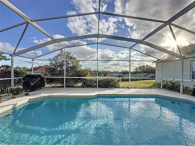 view of swimming pool with glass enclosure and grilling area