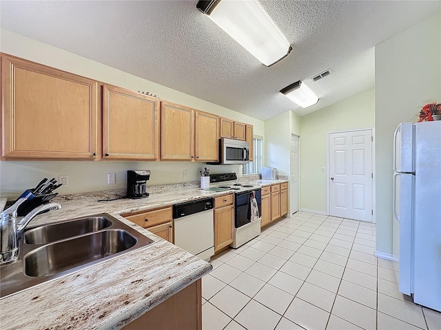 kitchen with lofted ceiling, white appliances, sink, light tile patterned floors, and a textured ceiling