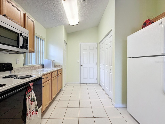 kitchen featuring a textured ceiling, light tile patterned flooring, and white appliances