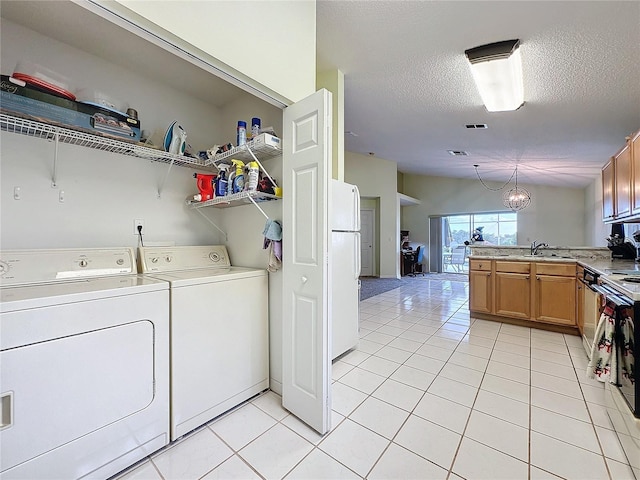 washroom featuring a textured ceiling, sink, an inviting chandelier, independent washer and dryer, and light tile patterned flooring