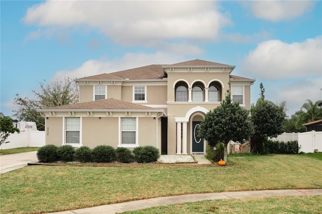 mediterranean / spanish-style house featuring stucco siding, a front lawn, and fence