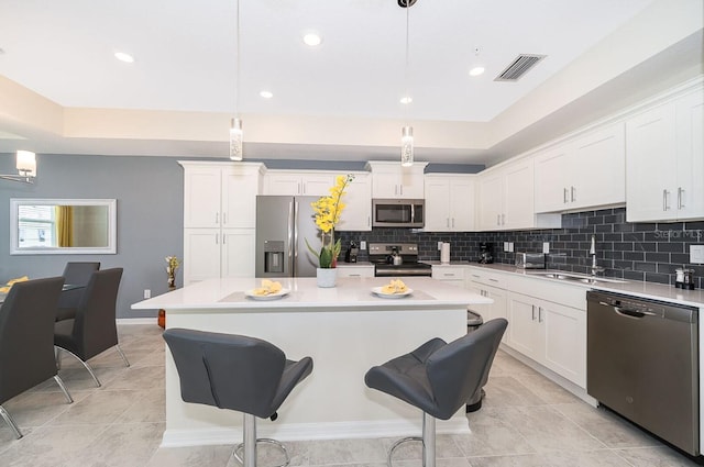 kitchen featuring white cabinetry, sink, hanging light fixtures, and appliances with stainless steel finishes