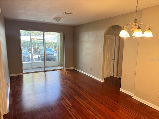 empty room featuring dark hardwood / wood-style flooring and a notable chandelier