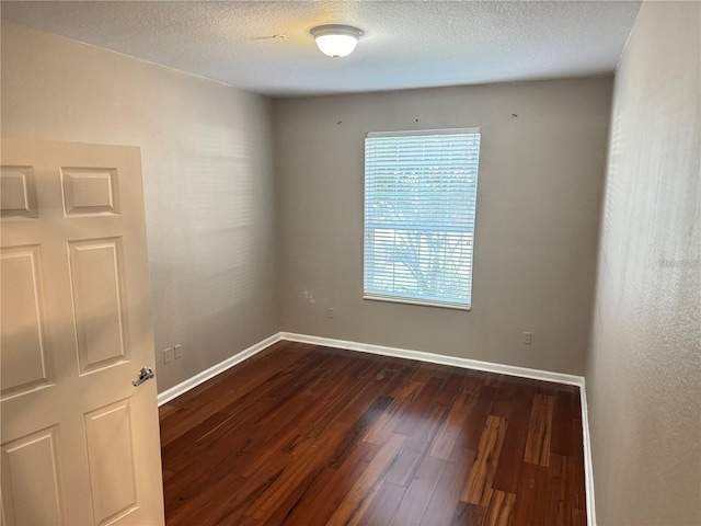 empty room featuring dark hardwood / wood-style floors and a textured ceiling