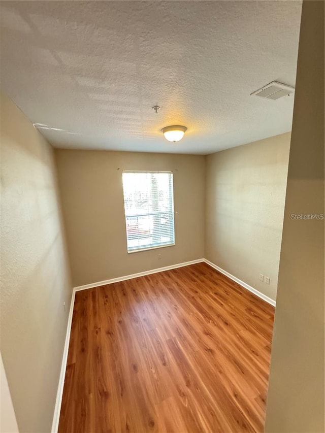 spare room with hardwood / wood-style floors and a textured ceiling