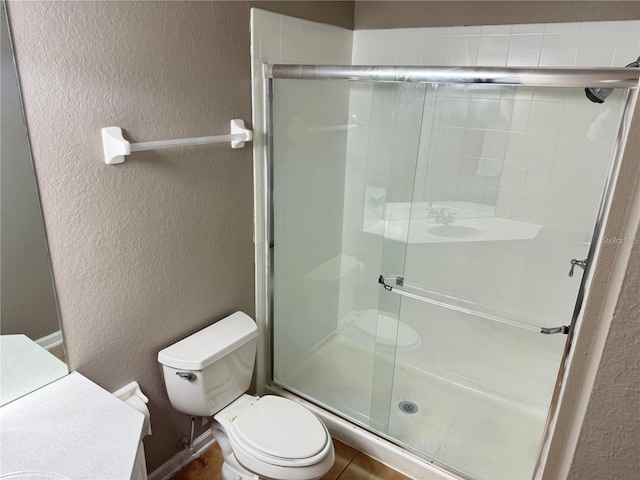 bathroom featuring vanity, a shower with door, and toilet