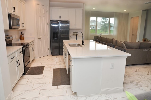 kitchen with appliances with stainless steel finishes, an island with sink, white cabinets, and sink