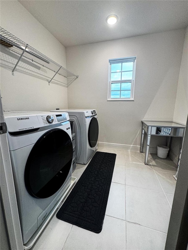 laundry area with washer and dryer and light tile patterned floors