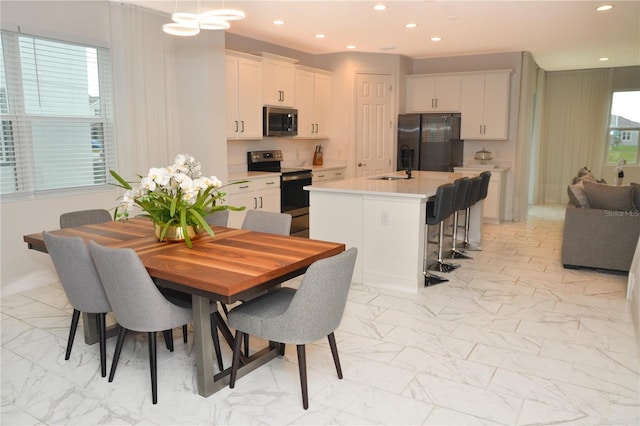 kitchen featuring sink, a center island with sink, white cabinets, and appliances with stainless steel finishes