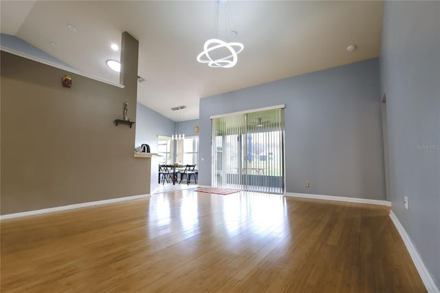 unfurnished living room with a chandelier, lofted ceiling, and wood-type flooring