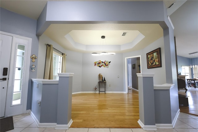 tiled foyer featuring a healthy amount of sunlight and a tray ceiling