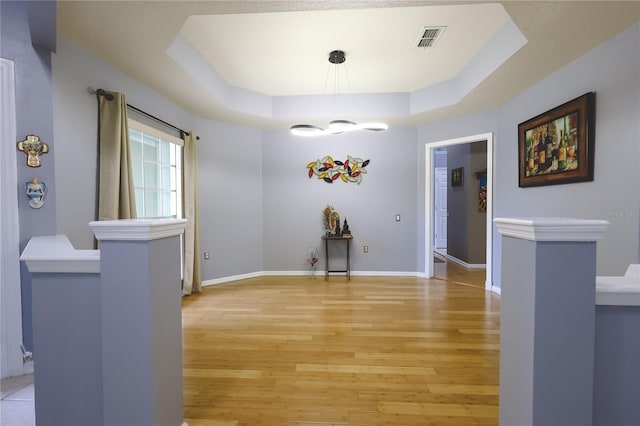 unfurnished dining area featuring a tray ceiling and light hardwood / wood-style floors