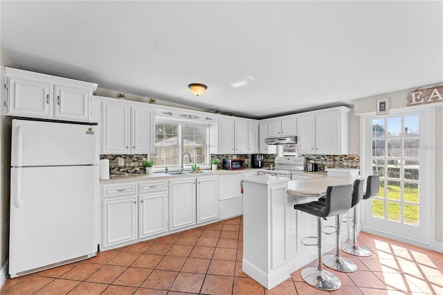 kitchen with white appliances, white cabinetry, and a wealth of natural light