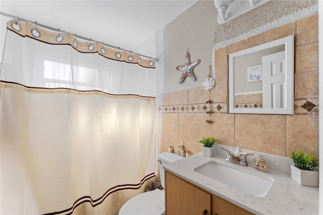 bathroom with vanity, toilet, and tile walls