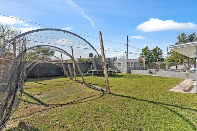 view of yard with a trampoline and a storage unit