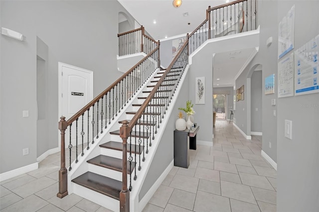 stairs featuring a towering ceiling and tile patterned floors