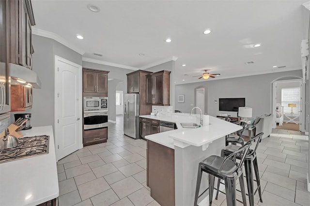 kitchen featuring a breakfast bar, kitchen peninsula, sink, stainless steel appliances, and light tile patterned floors