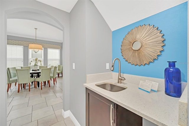 kitchen with light stone countertops, sink, pendant lighting, and light tile patterned floors