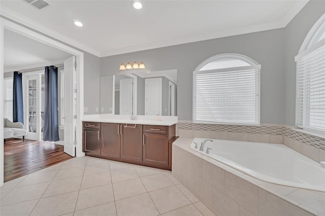 bathroom featuring tiled bath, vanity, ornamental molding, and tile patterned flooring