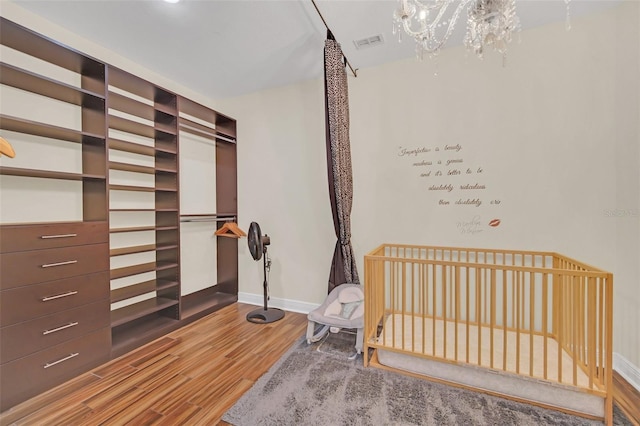 bedroom with wood-type flooring and a nursery area