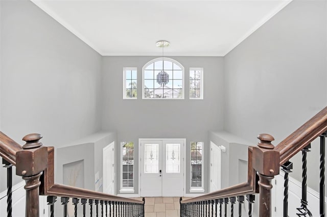 tiled entryway with crown molding and a chandelier