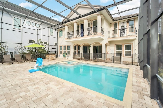 view of pool with an in ground hot tub, glass enclosure, and a patio