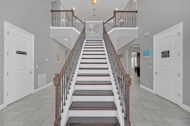 stairs featuring tile patterned flooring and a towering ceiling